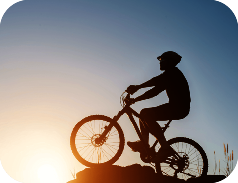 atlantis dx - Hermann Hartje KG: Implementierung Middleware und CRM System Foto: Silhouette eines Radfahrers mit Helm auf dem Gipfel eines Berges, blauer Himmel mit untergehender Sonne