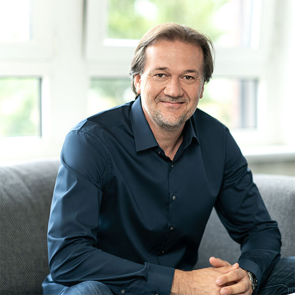 atlantis dx - Michael Märtin, Geschäftsführer Foto: Frontalaufnahme von Michael Märtin, trägt ein schwarzes Hemd, sitzt entspannt im Pausenraum, lächelt