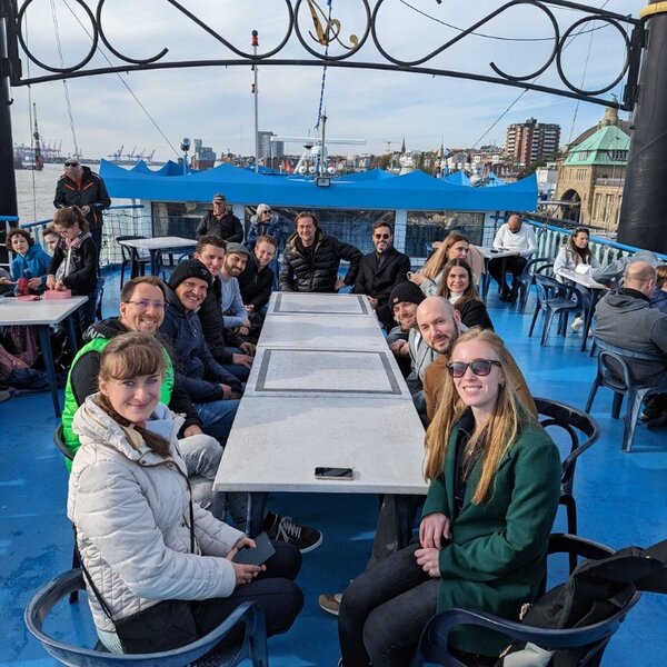 Foto: atlantis dx Team und Produktpartner Ibexa sitzen an Deck auf einer Hafenrundfahrt