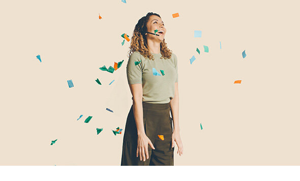 atlantis dx - Zendesk Support Suite Foto: Frau mit Headset steht lachend vor hellem Hintergrund, es regnet Konfetti