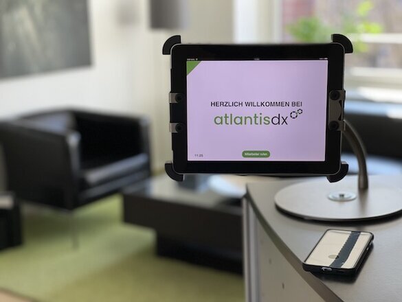 atlantis dx - Kontakt Foto: Tresen im Eingangsbereich von atlantis dx mit Tablet, Nahaufnahme vom Tablet mit Begrüßungstext Herzlich willkommen bei atlantis dx