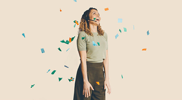 atlantis dx - Zendesk Support Suite Foto: Frau mit Headset steht lachend vor hellem Hintergrund, es regnet Konfetti