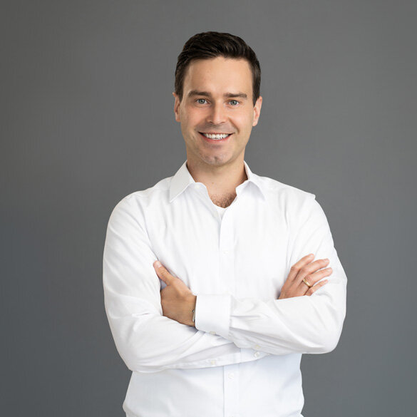 atlantis dx - Radek Paluszak, Geschäftsleitung | Partner Foto: Frontalaufnahme von Radek Paluszak, lächelt, weißes Hemd, Hintergrund dunkel
