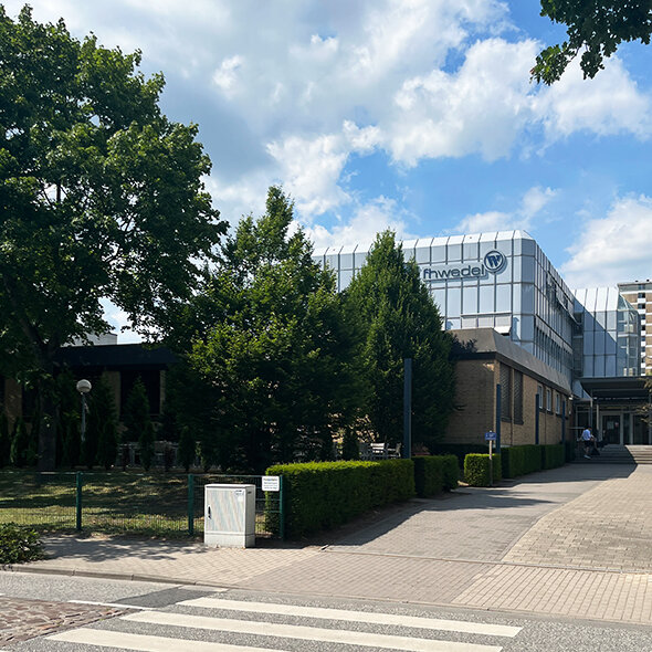 atlantis dx - Kooperation mit der FH Wedel Foto: Gebäude der FH Wedel von schräg vorne, Bäume und blauer Himmel