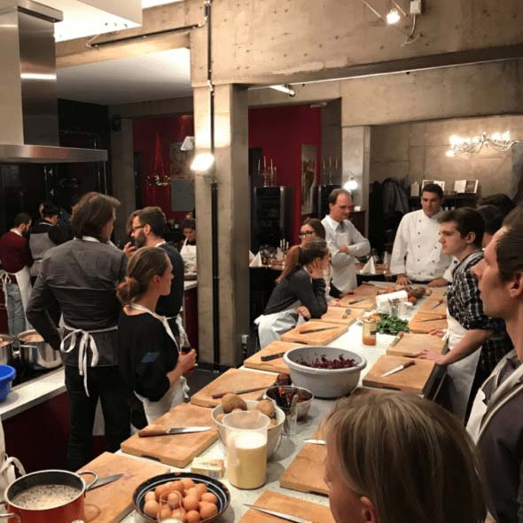 Foto: Mitarbeiter von atlantis dx stehen in der Küche am Tresen und bekommen Anweisungen vom Koch