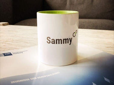 Foto: Weißer Becher mit grüner Innenseite, beschriftet mit 'Sammy' und atlantis dx Bildmarke