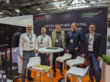 E-Commerce Berlin Expo 2023 with Ibexa Photo: 5 people posing in front of an exhibition wall